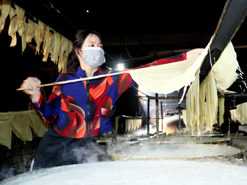 Người thợ vớt lá tàu hũ lên giàn phơi. (Ảnh: Lê Thúy Hằng/TTXVN)