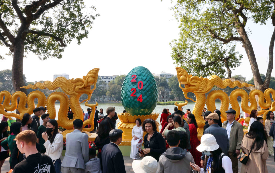 Người dân Thủ đô và du khách ghi lại khoảnh khắc đầu Năm mới bên cạnh biểu tượng hình rồng hay tiểu cảnh 2024 tại khu vực hồ Hoàn Kiếm. (Ảnh: Phạm Kiên/TTXVN)