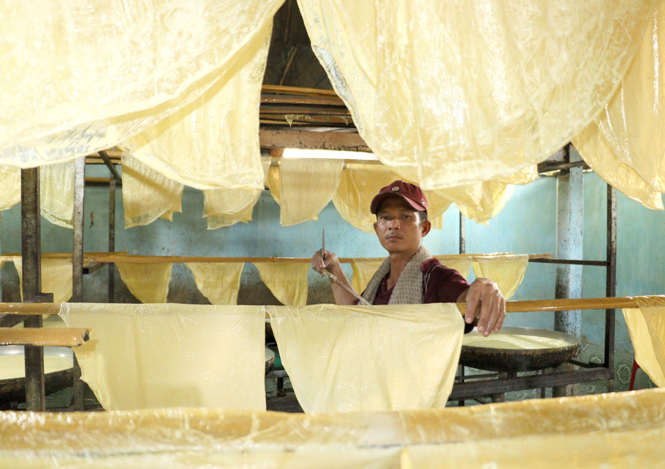 Người thợ vớt lá tàu hũ lên giàn phơi. (Ảnh: Lê Thúy Hằng/TTXVN)