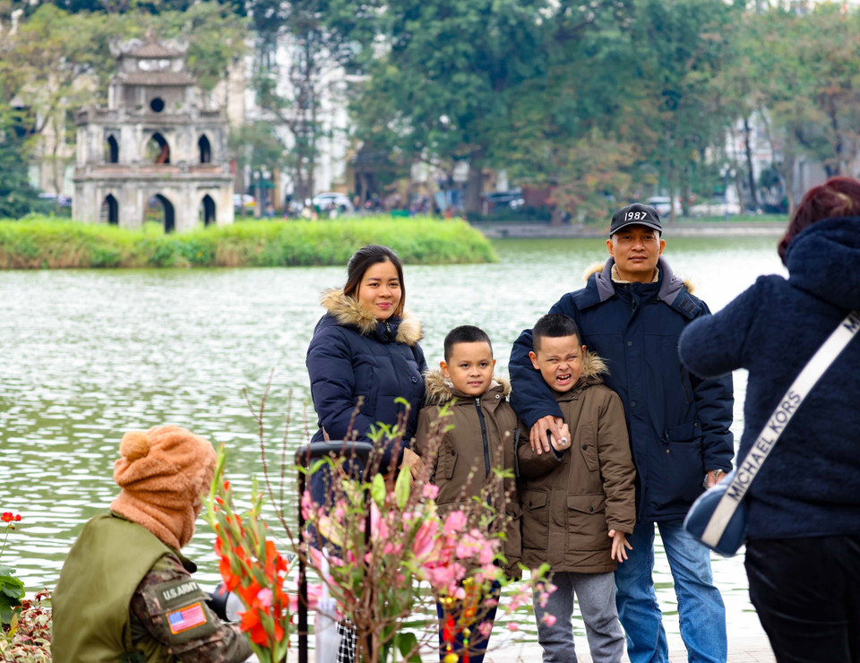 Một gia đình về Hà Nội đón Tết lưu lại khoảnh khắc đẹp bên hồ Hoàn Kiếm với tháp Rùa cổ kính, rêu phong. (Ảnh: Thanh Tùng/TTXVN)
