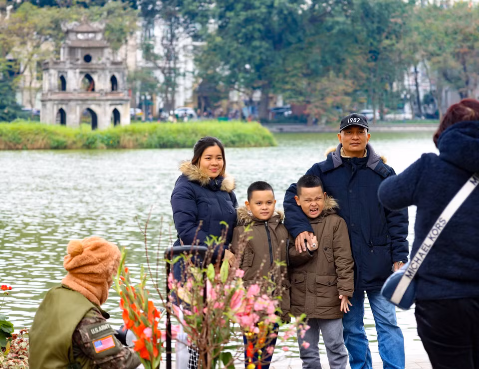 Một gia đình về Hà Nội đón Tết lưu lại khoảnh khắc đẹp bên hồ Hoàn Kiếm với tháp Rùa cổ kính, rêu phong. (Ảnh: Thanh Tùng/TTXVN)