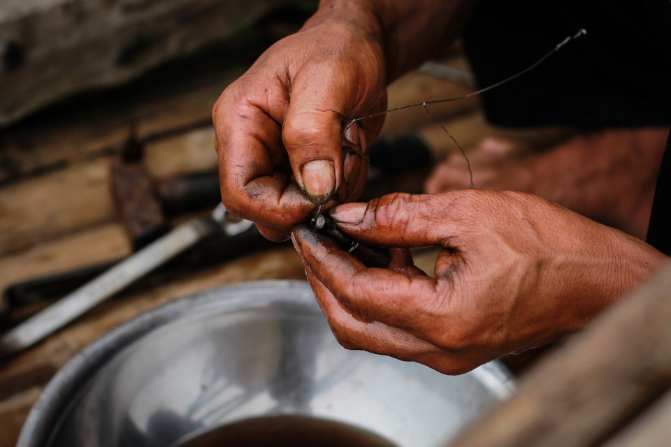 Người ngư dân khéo léo sửa chữa con thuyền tự tay mình đóng. Biển to sóng lớn, tàu thuyền nhỏ bé lại thô sơ, việc hỏng hóc xảy ra thường xuyên, việc sửa chữa cũng trở nên thành thạo và quen thuộc hơn. (Ảnh: Thanh Dung/Vietnam+)
