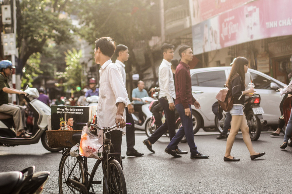 Bức ảnh quảng cáo đầy khỏe khoắn có vẻ đối lập với dáng người hom hem của người đàn ông bán hàng rong. (Ảnh: Thanh Dung/Vietnam+)