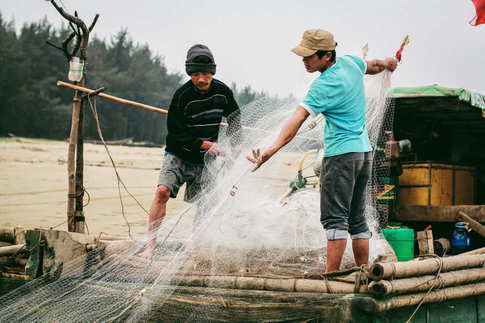 Những người ngư dân gỡ lưới chuẩn bị cho chuyến đi biển hôm sau. (Ảnh: Thanh Dung/Vietnam+)