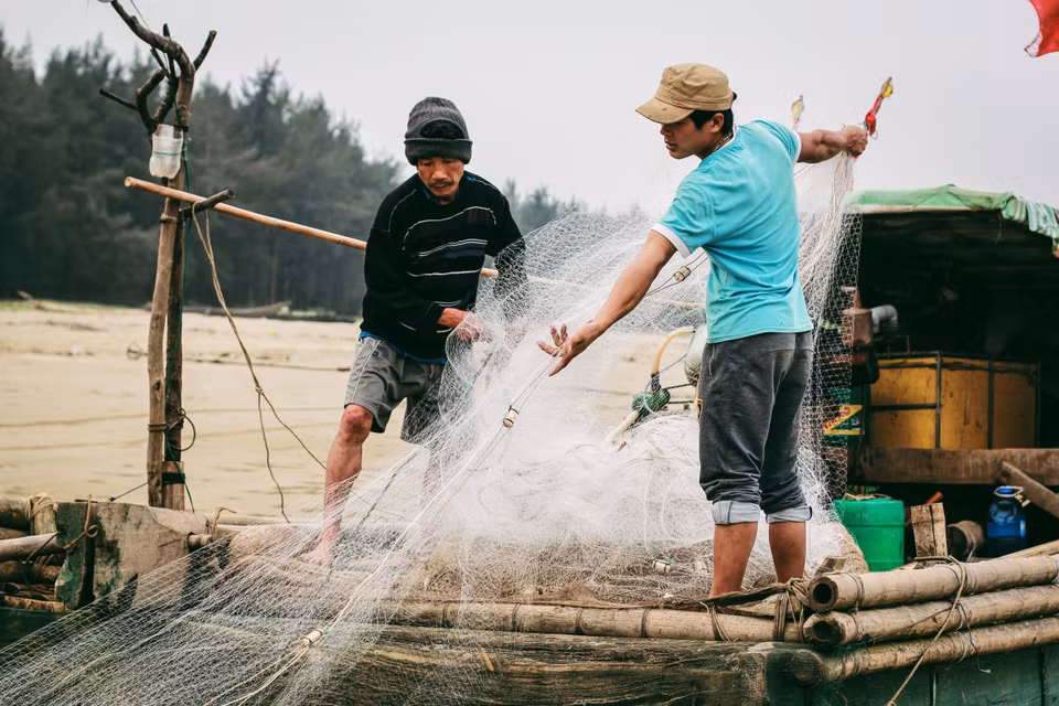 Những người ngư dân gỡ lưới chuẩn bị cho chuyến đi biển hôm sau. (Ảnh: Thanh Dung/Vietnam+)