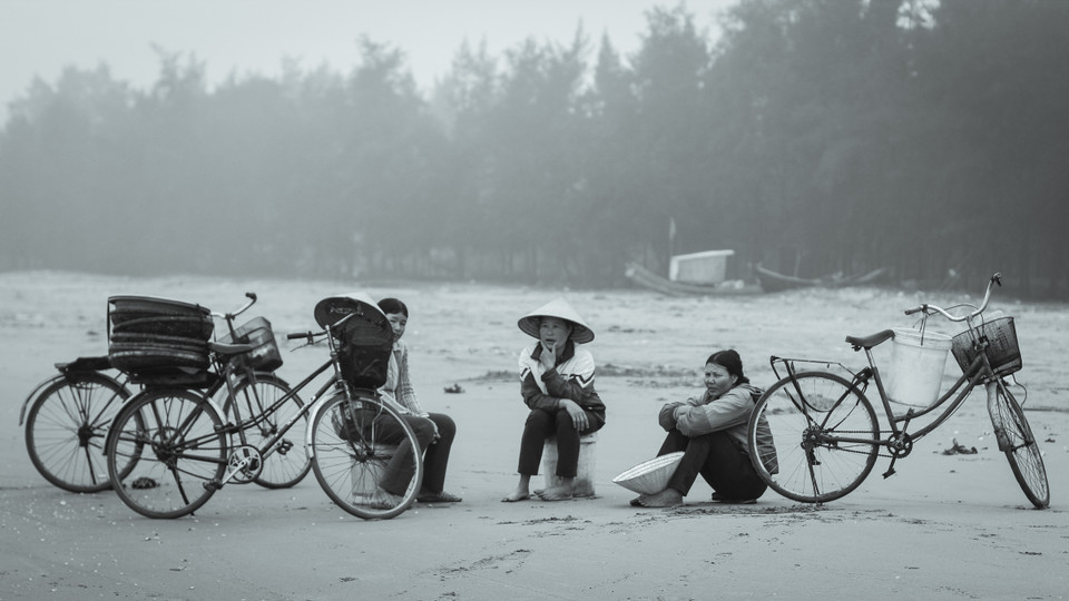 Những người thu mua hải sản trò chuyện trong lúc đợi tàu về. Tàu thường trở về lúc 7-9 giờ sáng. (Ảnh: Thanh Dung/Vietnam+)