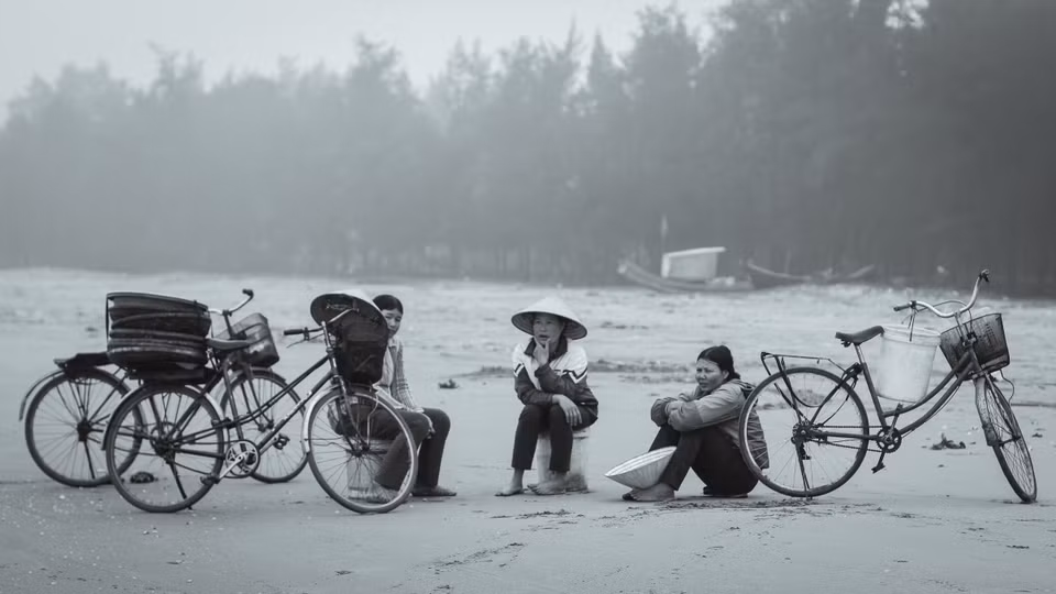 Những người thu mua hải sản trò chuyện trong lúc đợi tàu về. Tàu thường trở về lúc 7-9 giờ sáng. (Ảnh: Thanh Dung/Vietnam+)
