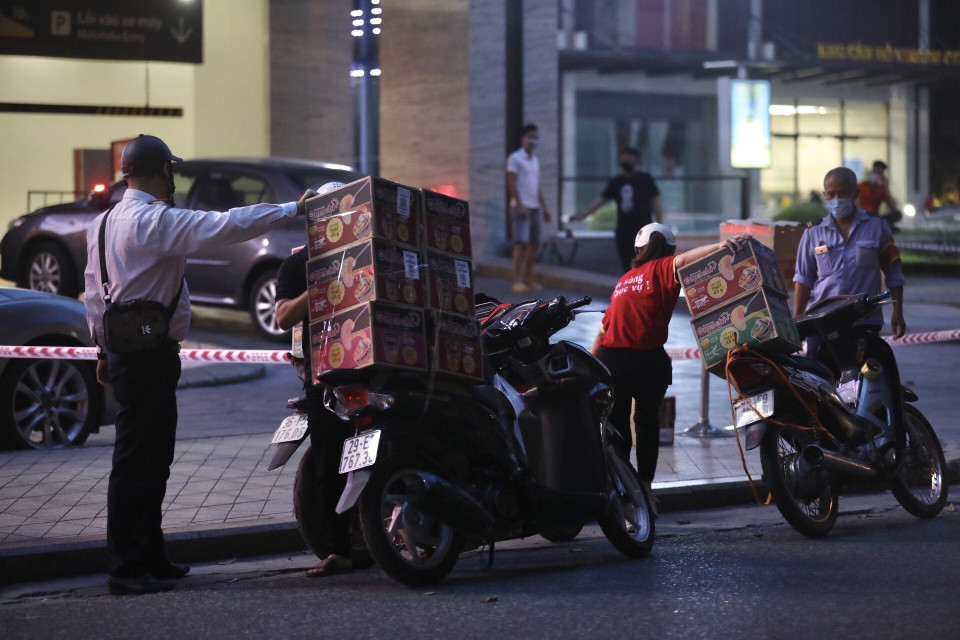 Người dân mang đồ tiếp tế cho người bị cách lý bên trong toà nhà. (Ảnh: Minh Quyết/TTXVN)