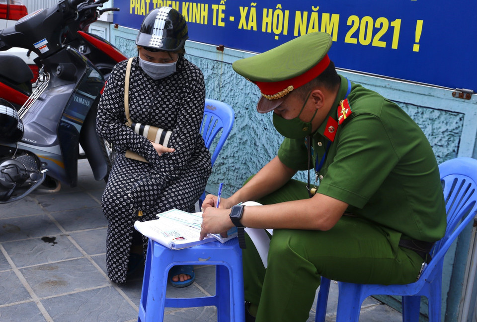 Công an phường Cầu Dền (quận Hai Bà Trưng) xử phạt người dân ra đường không có lý do chính đáng, sáng 26/7. (Ảnh: Hoàng Hiếu/TTXVN)