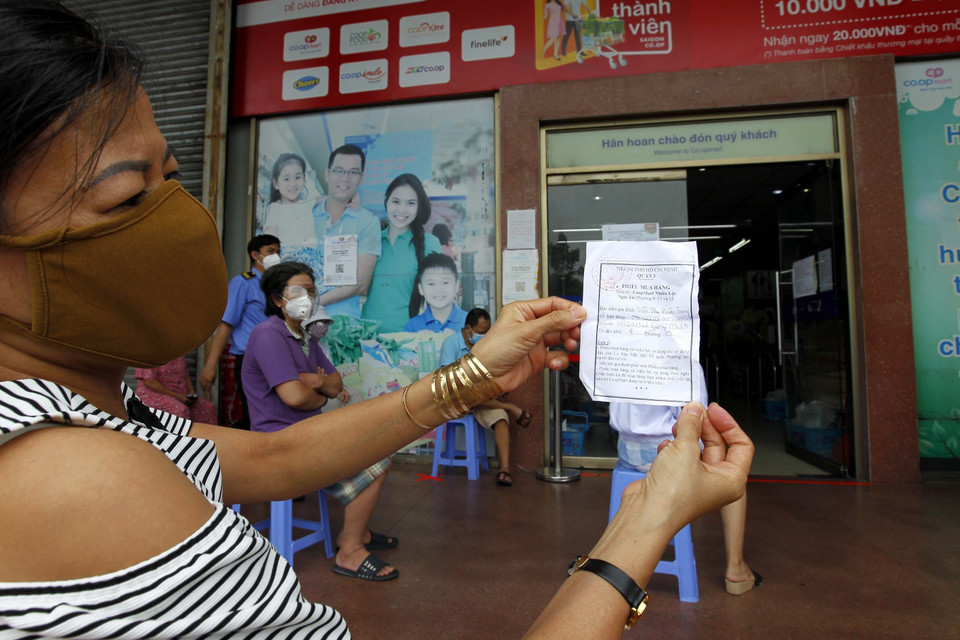 Người dân Quận 3 được phát phiếu mua sắm tại Hệ thống siêu thị Co.op mart Nhiêu Lộc-Thị Nghè (Liên Hiệp Hợp tác xã thương mại Thành phố Hồ Chí Minh) để đảm bảo an toàn phòng chống dịch. (Ảnh: Thanh Vũ/TTXVN)