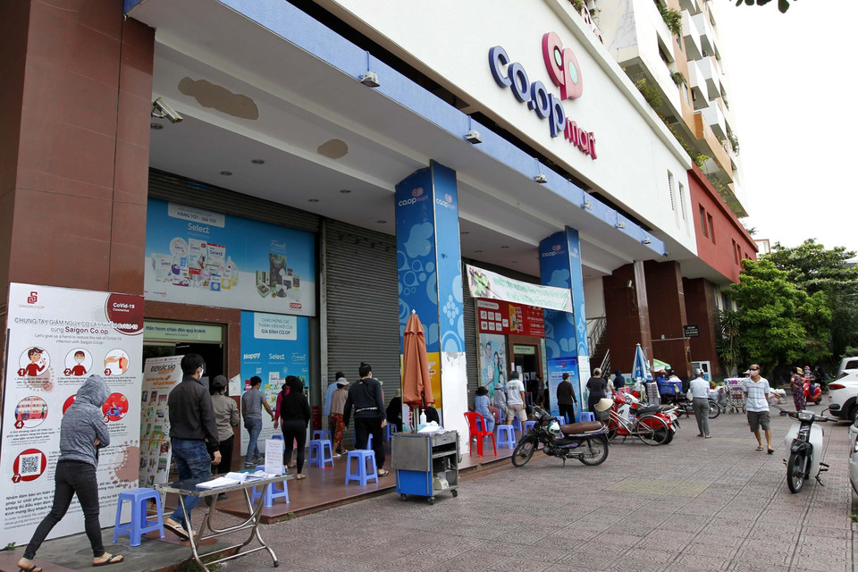Người dân thành phố tuân thủ các biện pháp an toàn phòng chống dịch bệnh trước khi vào mua sắm tại Hệ thống siêu thị Saigon Co.op. (Ảnh: Thanh Vũ/TTXVN)