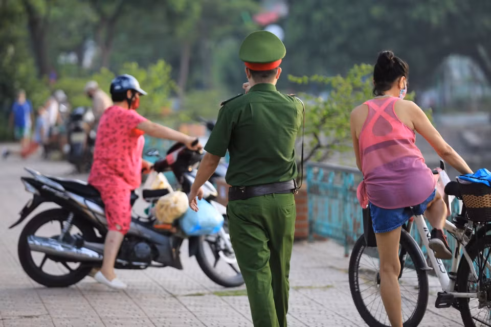 Lực lượng công an phường Thụy Khuê nhắc nhở người dân không tập thể dục tại đường Thanh Niên (Ảnh chụp 6h sáng 19/7). (Ảnh: Thành Đạt/TTXVN)