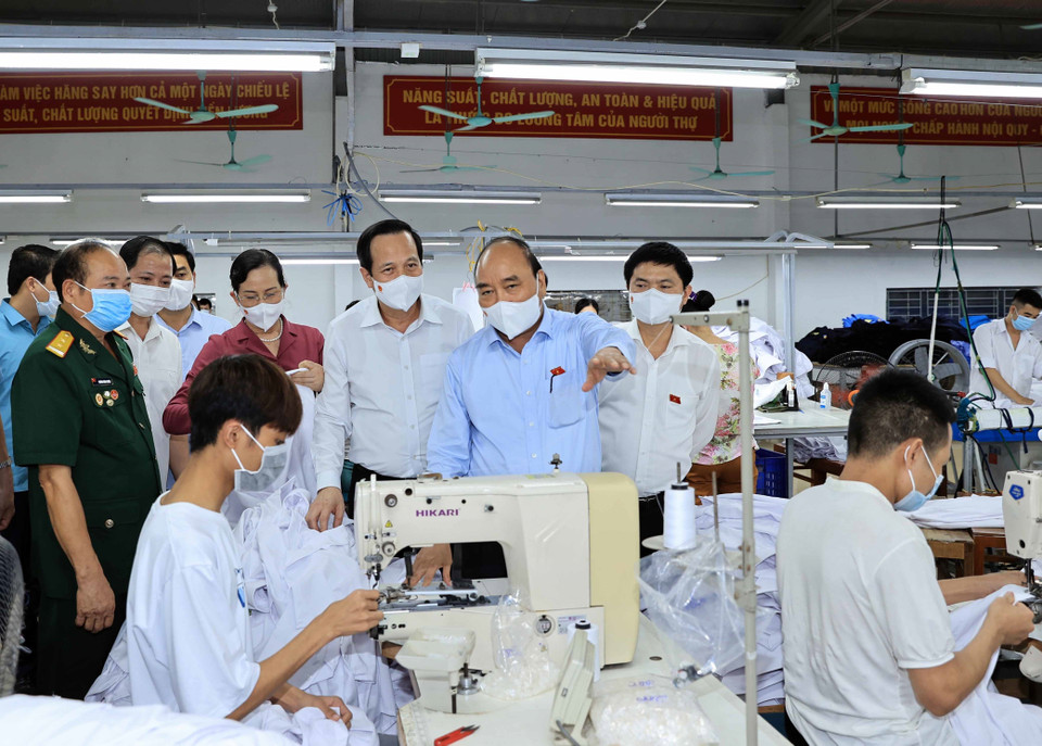 Chủ tịch nước Nguyễn Xuân Phúc đến thăm hỏi và tặng quà cho thương binh làm kinh tế giỏi Hoàng Văn Tuyên chủ doanh nghiệp may mặc Hoàng Tuyên. (Ảnh: Thống Nhất/TTXVN)