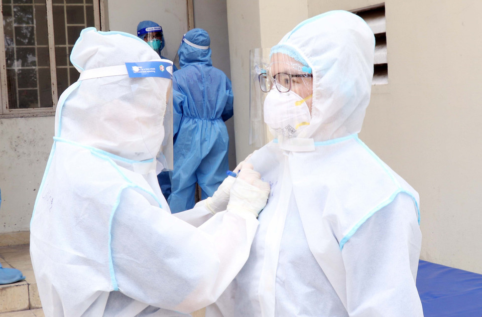 Điều dưỡng tại Bệnh viện dã chiến thu dung, điều trị COVID-19 số 4 (xã Vĩnh Lộc B, huyện Bình Chánh) nhờ đồng nghiệp ghi tên lên áo để chuẩn bị tiếp nhận bệnh nhân. (Ảnh: Xuân Khu/TTXVN)