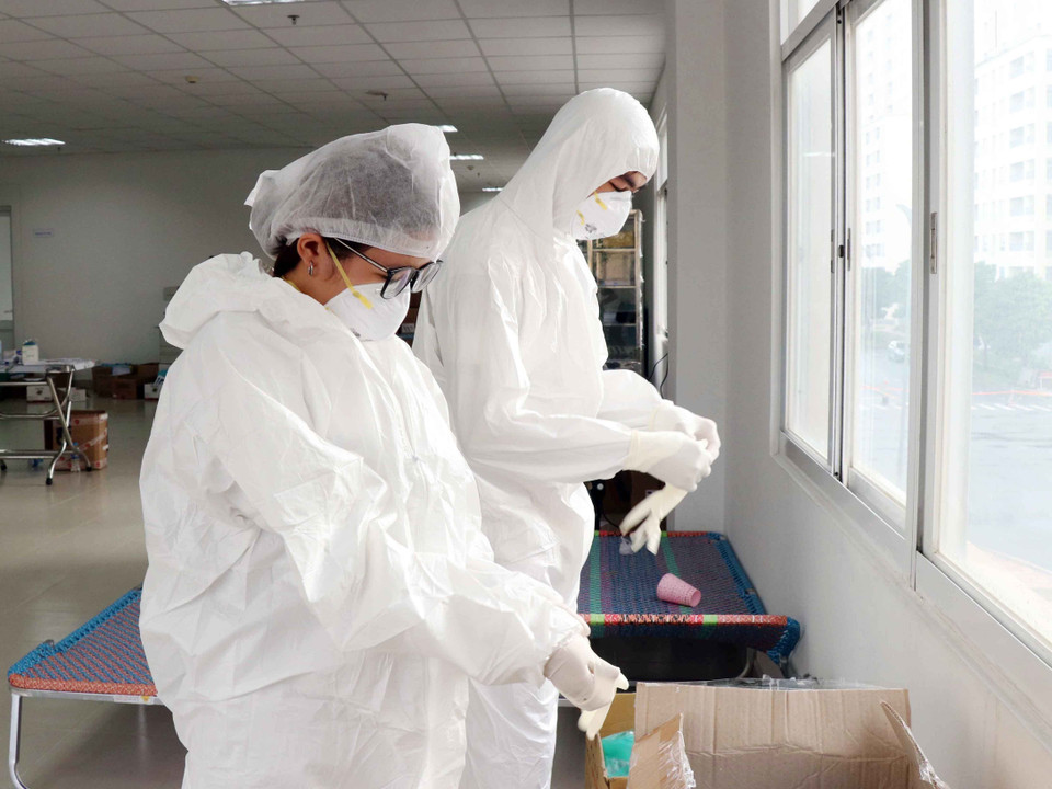 Mặc bộ đồ bảo hiểm phòng dịch với 3 chiếc găng cho mỗi bên tay, các y, bác sỹ bước vào ca trực chăm sóc bệnh nhân nhiễm COVID-19. (Ảnh: Xuân Khu/TTXVN)