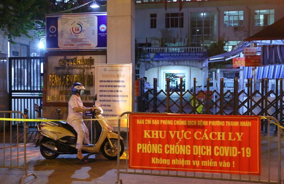 Một nhân viên phải đứng ngoài sau khi bệnh viện Phổi bị cách ly tạm thời. (Ảnh: Hoàng Hiếu/TTXVN)