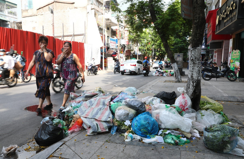 Cái nắng lên tới 40 độ C khiến cho những đống rác này bốc mùi hôi thối nồng nặng, khiến người qua đường chỉ biết "nhắm mắt nín thở" tại phố Đội Cấn (ảnh chụp ngày 16/7). (Ảnh: Thành Đạt/TTXVN)
