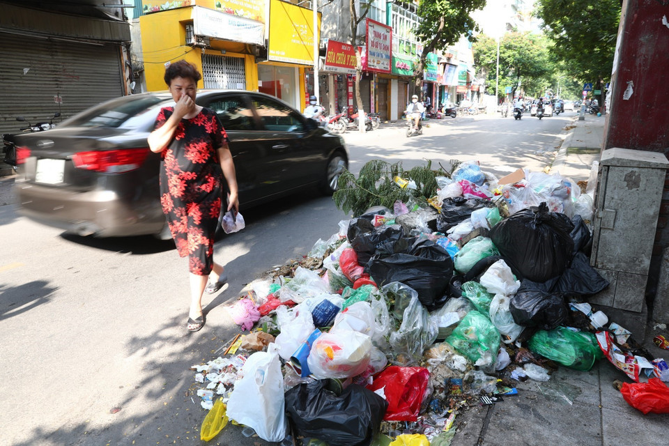 Cái nắng lên tới 40 độ C khiến cho những đống rác này bốc mùi hôi thối nồng nặng, khiến người qua đường chỉ biết "nhắm mắt nín thở" tại phố Đội Cấn (ảnh chụp ngày 16/7). (Ảnh: Thành Đạt/TTXVN)