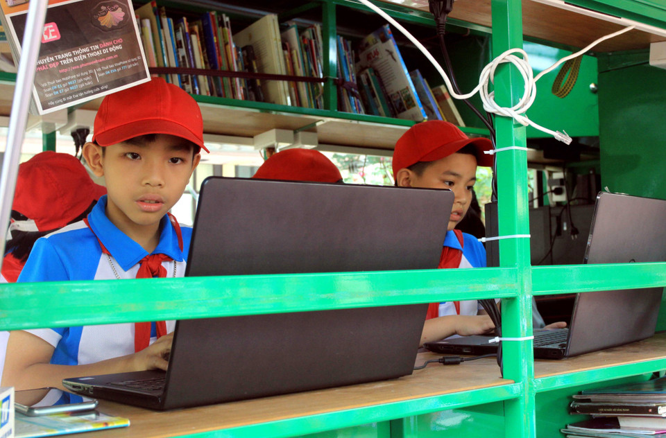 Các em học sinh tra cứu thông tin từ máy tính tại thư viện lưu động. (Ảnh: Thế Duyệt/TTXVN)