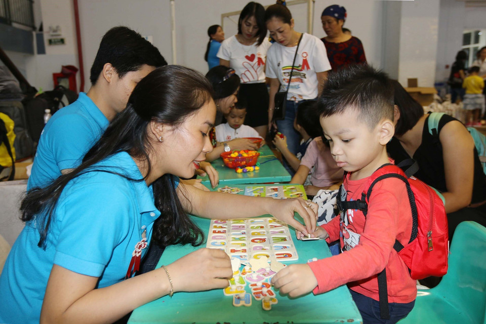 Cô giáo hướng dẫn trẻ tự kỷ tham gia trò chơi xếp chữ thực hành tại Ngày hội tri ân giáo viên trẻ tự kỷ. (Ảnh: Thanh Vũ/TTXVN)