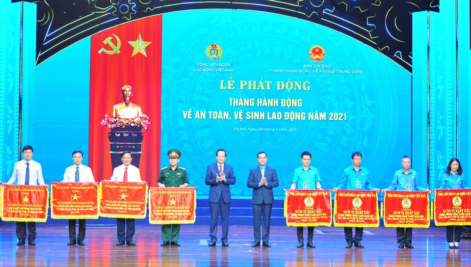 Bộ trưởng Bộ Lao động, Thương binh và Xã hội Đào Ngọc Dung và Chủ tịch Tổng Liên đoàn Lao động Việt Nam Nguyễn Đình Khang trao Cờ thì đua của Tổng Liên đoàn Lao động Việt Nam cho các tập thể xuất sắc. (Ảnh:Minh Đức/ TTXVN)