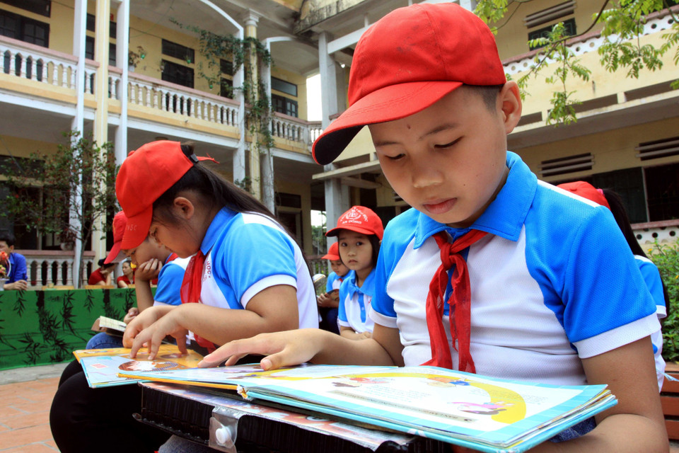 Học sinh trường Tiểu học An Đồng (Quỳnh Phụ, Thái Bình) đọc sách từ thư viện lưu động. (Ảnh: Thế Duyệt/TTXVN)