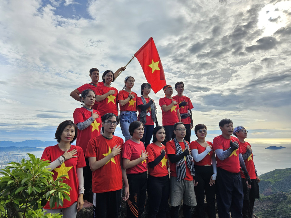 Nhóm du khách chinh phục núi Hoàng Ngưu Sơn và làm lễ chào cờ trên đỉnh núi. (Ảnh: Phan Sáu/TTXVN)