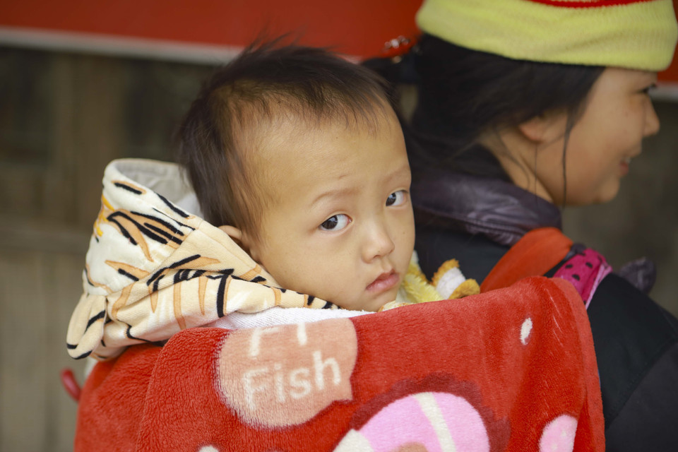 Một đứa trẻ được ủ trong chăn ấm địu sau lưng mẹ. (Ảnh: Xuân Tư/TTXVN)