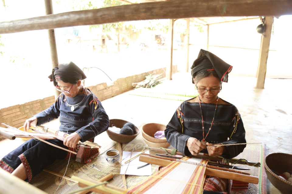 Nghệ nhân Đinh Thị Hiền (bên phải) tỉ mẩn với công việc dệt vải - một trong những công đoạn để lưu truyền cho thế hệ mai sau. (Ảnh: Quang Thái/TTXVN)