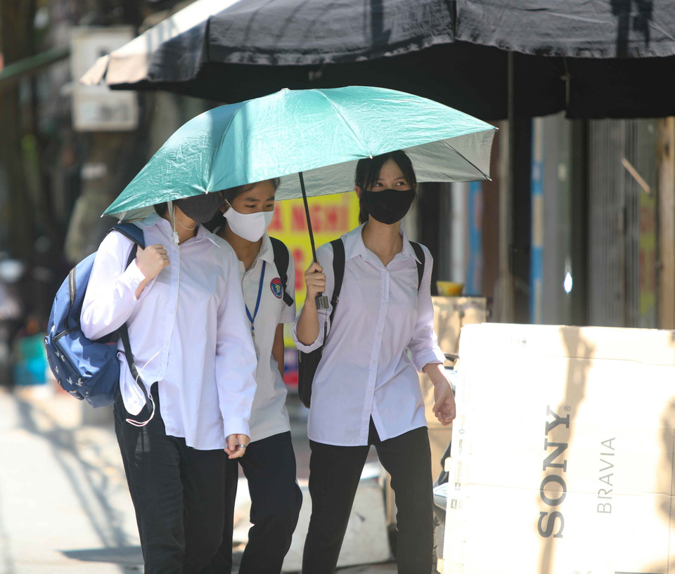 Học sinh sử dụng ô che nắng khi tới trường. (Ảnh: Thanh Tùng/TTXVN)