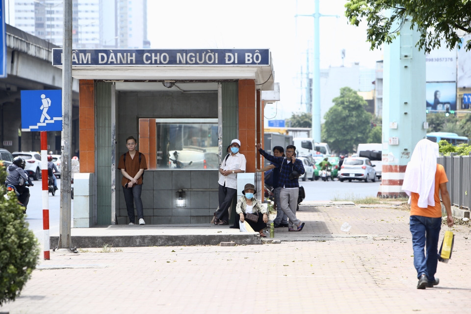 Người dân tranh thủ tránh nắng khi chờ xe buýt. (Ảnh: Minh Quyết/TTXVN)