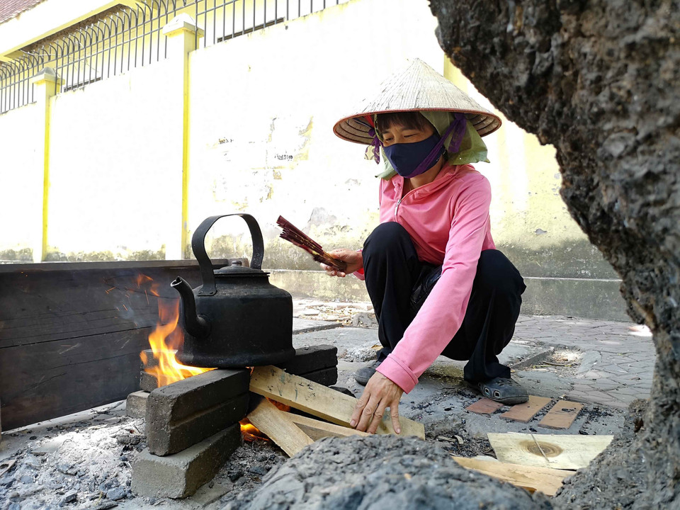 Cũng vì mưu sinh mà trong thời tiết nắng nóng, người phụ nữ bán nước này vẫn phải sử dụng bếp củi để đun nước, hãm trà bán. (Ảnh: Thanh Tùng/TTXVN)