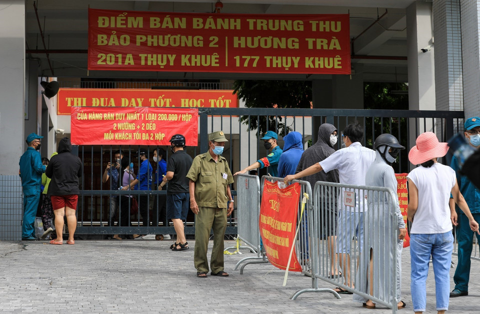 Lực lượng dân phòng hướng dẫn người dân xếp hàng đảm bảo giãn khoảng cách cần thiết, mỗi lượt vào mua bánh chỉ cho 10 người vào. (Ảnh: Thành Đạt/TTXVN)
