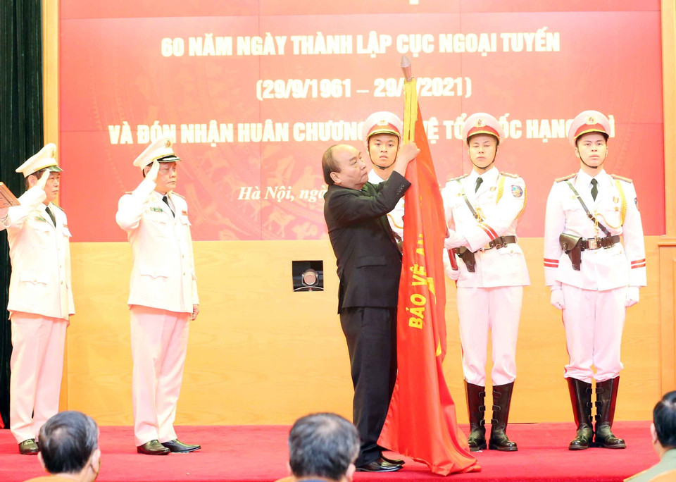 Chủ tịch nước Nguyễn Xuân Phúc gắn Huân chương Bảo vệ Tổ quốc hạng Nhì lên cờ truyền thống của Cục Ngoại tuyến. (Ảnh: Phạm Kiên/TTXVN)