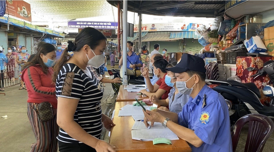 Tại chợ Cồn nhiều tiểu thương xếp hàng lấy thẻ buôn bán luân phiên tại chợ. (Ảnh: Văn Dũng/TTXVN)