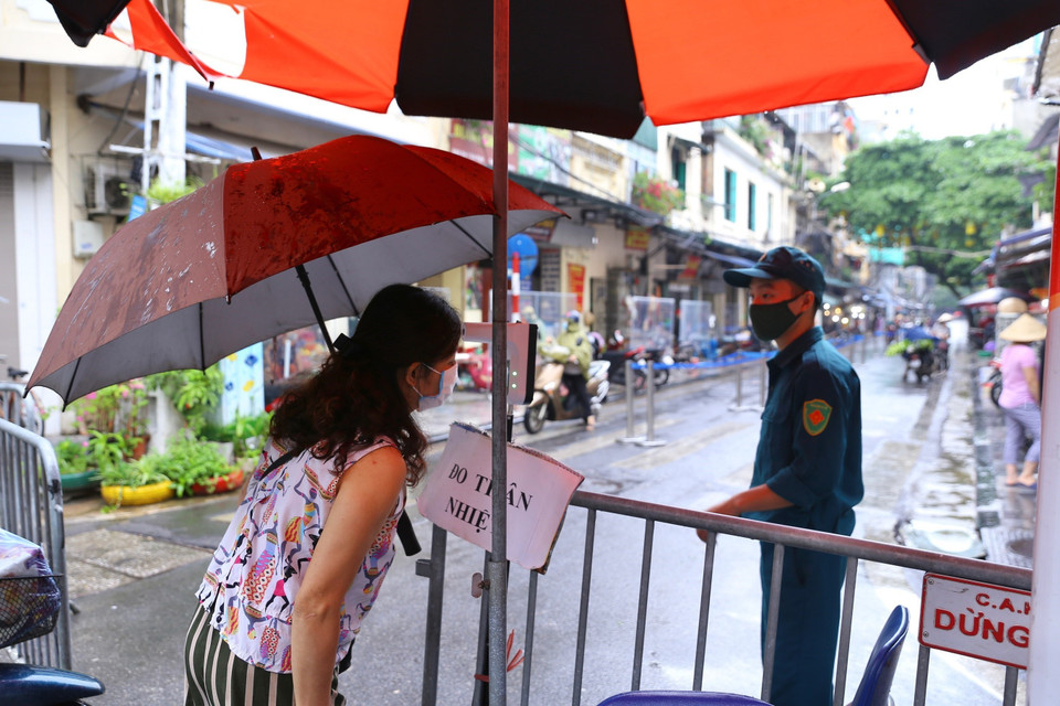 Người dân được kiểm tra thân nhiệt để rà soát phòng COVID-19 trước khi vào chợ Hàng Bè (Hàng Bạc, Hoàn Kiếm). (Ảnh: Hoàng Hiếu/TTXVN)