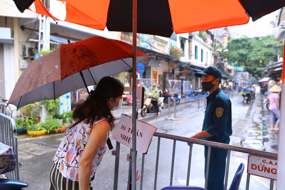 Người dân được kiểm tra thân nhiệt để rà soát phòng COVID-19 trước khi vào chợ Hàng Bè (Hàng Bạc, Hoàn Kiếm). (Ảnh: Hoàng Hiếu/TTXVN)