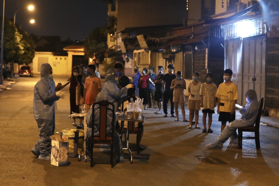 Nhân viên y tế lấy mẫu cho người dân tổ 7, phường Việt Hưng tối 19/9/2021. (Ảnh: Minh Quyết/TTXVN)