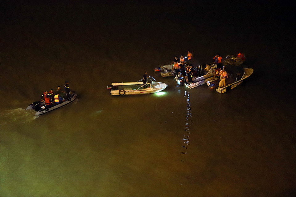 Lực lượng chức năng đang tiến hành tìm kiếm người chiếc ôtô bị nạn. (Ảnh: Hoàng Hùng/TTXVN)