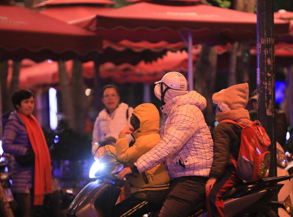 Một gia đình trang bị đồ ấm cho trẻ nhỏ khi di chuyển ngoài đường lúc 22h. (Ảnh: Hoàng Hiếu/TTXVN)