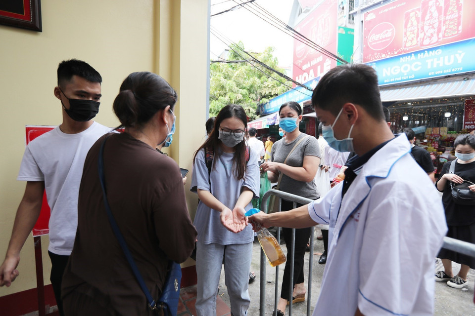 Lực lượng Y tế nhắc nhở người dân rửa tay sát khuẩn phòng chống dịch trước khi vào lễ tại Phủ Tây Hồ. (Ảnh: Thành Đạt/TTXVN)