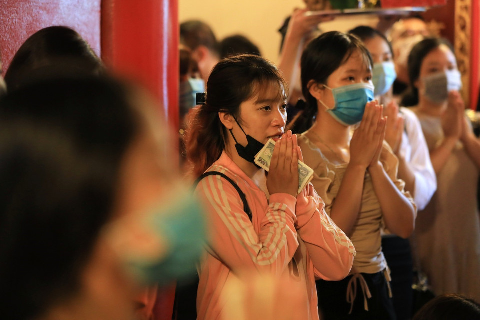 Một số người đi lễ không đeo khẩu trang không đúng quy cách. (Ảnh: Thành Đạt/TTXVN)