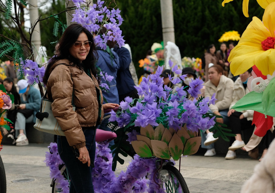 Một du khách chụp ảnh bên tác phẩm tham gia hội thi “Trang trí xe đạp hoa từ vật liệu tái chế.” (Ảnh: Nguyễn Dũng/TTXVN)