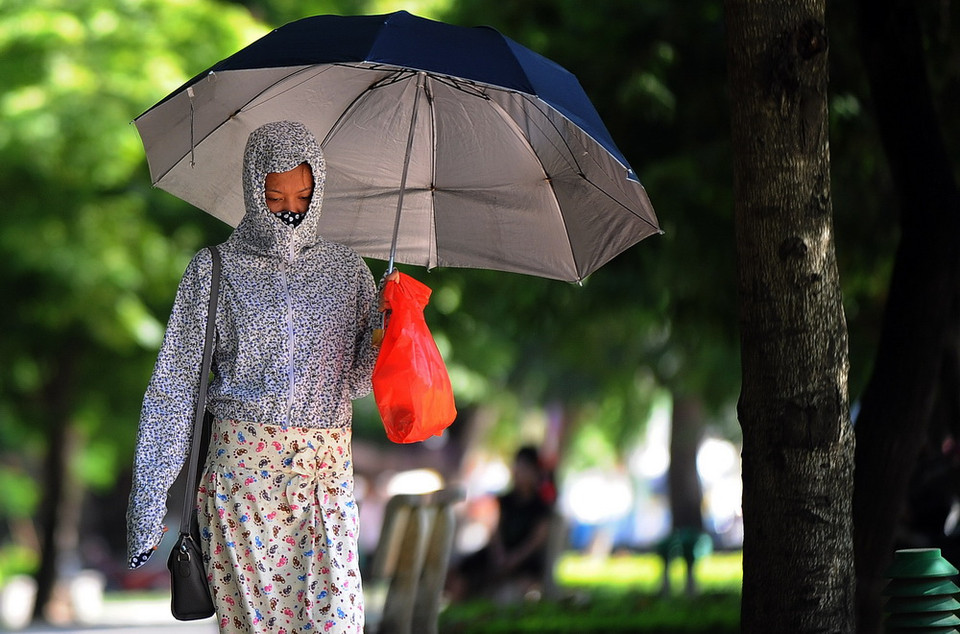 Chị em phụ nữ với những bộ 'thời trang bịt kín' khi tham gia giao thông trên đường phố. (Ảnh: Quang Quyết/TTXVN)