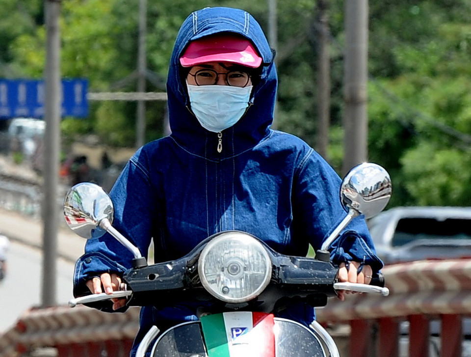 Chị em phụ nữ với những bộ 'thời trang bịt kín' khi tham gia giao thông trên đường phố. (Ảnh: Quang Quyết/TTXVN)