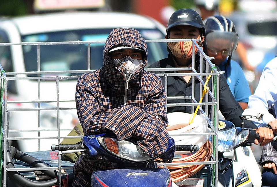 Chị em phụ nữ với những bộ 'thời trang bịt kín' khi tham gia giao thông trên đường phố. (Ảnh: Quang Quyết/TTXVN)