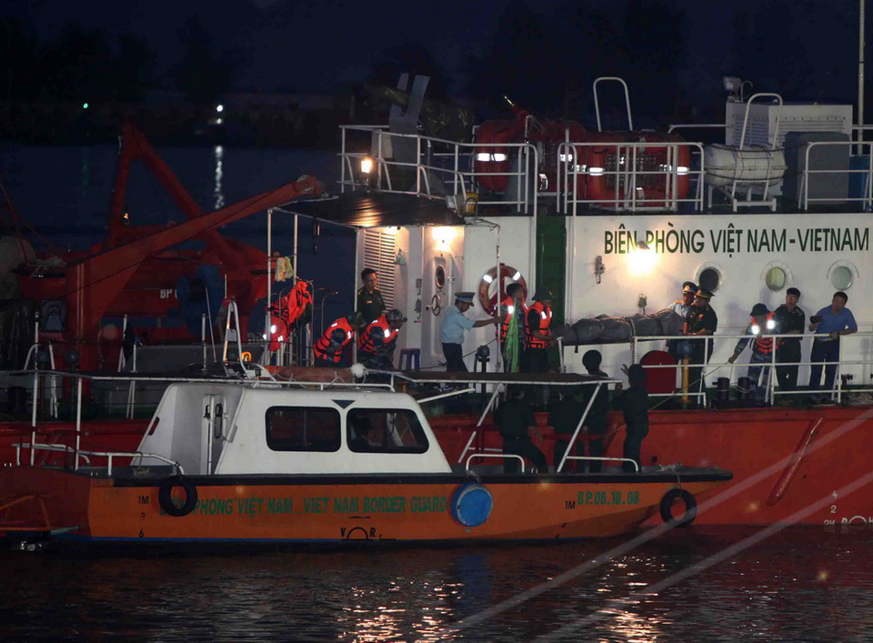 Đưa thi thể phi công Trần Quang Khải xuống canô để vào đất liền. (Ảnh: Thanh Tùng/TTXVN)