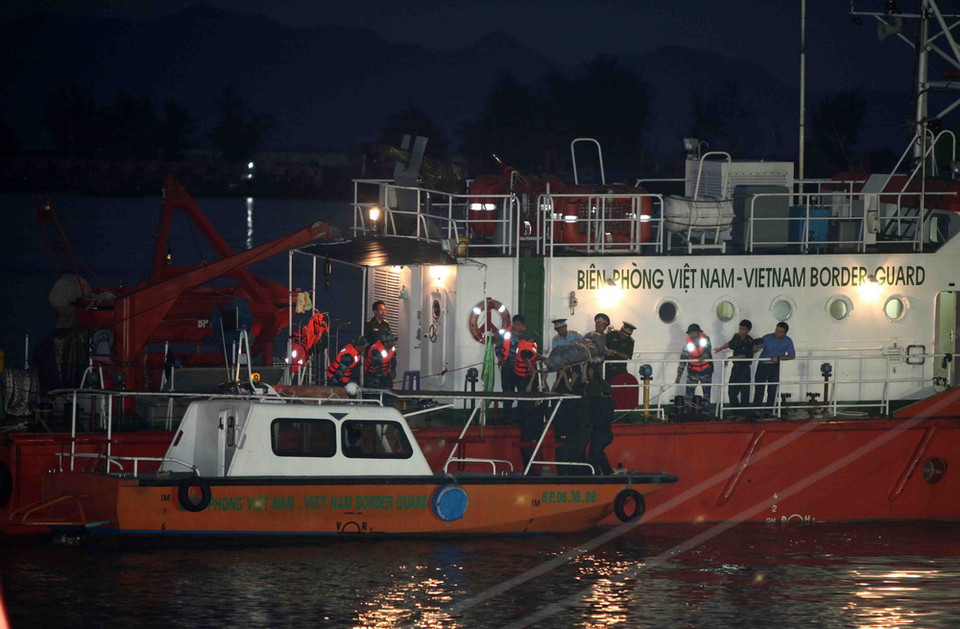 Đưa thi thể phi công Trần Quang Khải xuống canô để vào đất liền. (Ảnh: Thanh Tùng/TTXVN)