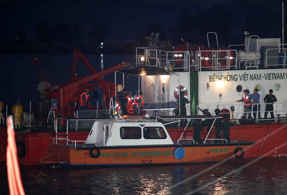 Đưa thi thể phi công Trần Quang Khải xuống canô để vào đất liền. (Ảnh: Thanh Tùng/TTXVN)