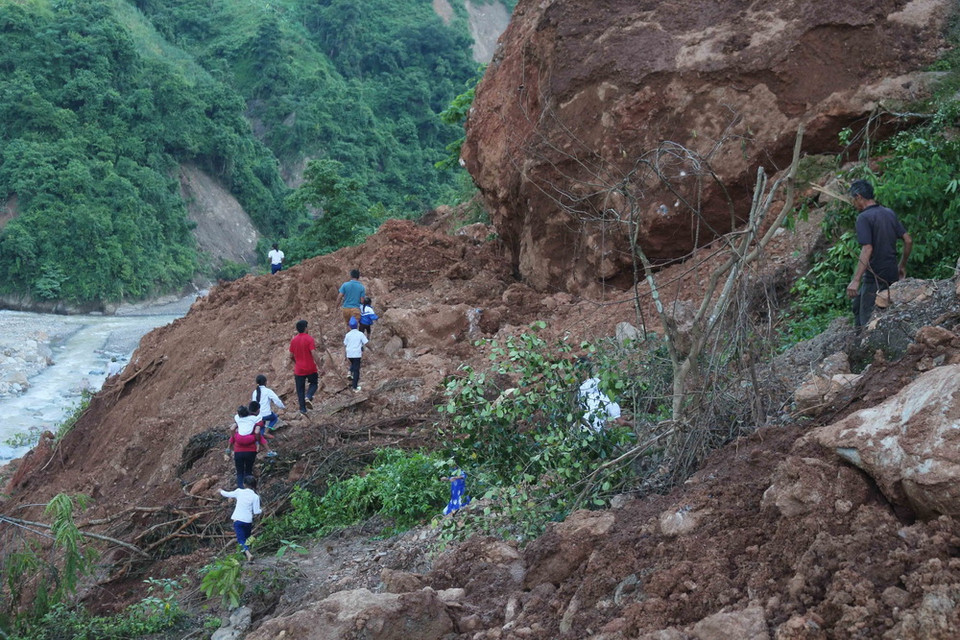 Các em học sinh phải đi bộ 1 giờ đồng hồ, băng qua những điểm sạt lở cực kỳ nguy hiểm để đến trường. (Ảnh: Nguyễn Oanh/TTXVN)